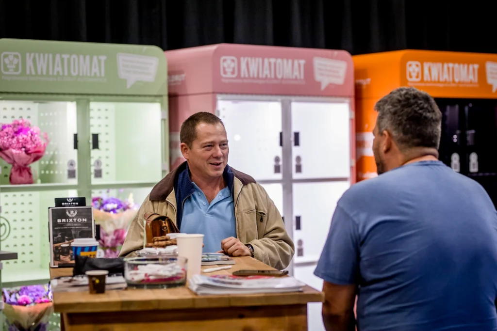 Business conversation between partners at a BouquetMat flower vending machine, discussing cooperation and modern floristry solutions by VendiFlor.